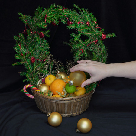 A large basket of fruit and Christmas balls. Crowned wreath of spruce branches. It is on the table. New Year of 2018.の写真素材