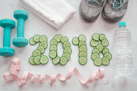 Sneakers, towel, water and dumbbells. Cucumber sliced symbol of the new year. Diet 2018.の写真素材