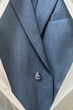 Business blue male suit in a white case with a zipper. Travel cover.