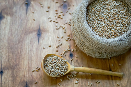 A bag of grain is on the table. There is a wooden spoon nearby. Autumn harvest.                      の写真素材