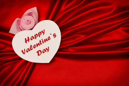 White heart with text, Happy Valentine's Day, on a red cloth. Waves in the form of bows. Love.の写真素材