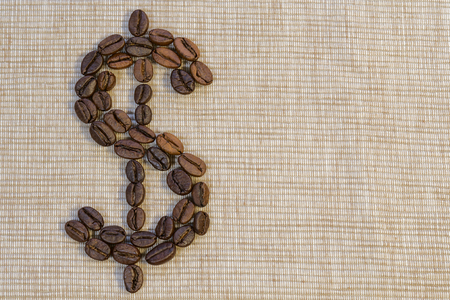 Coffee beans are laid out in the form of a dollar sign on a beige napkin. Symbol of growth, progress, recovery, financial well-being.の写真素材
