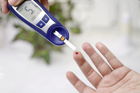 A medical test, checking a drop of blood on the sugar level. Pierce the finger with a lancet.の写真素材