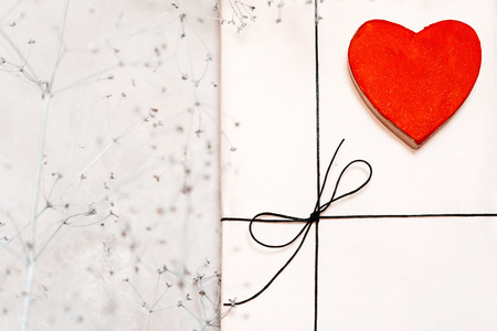 Gift box made of kraft paper, tied with lace. A wooden red heart and dry twigs. St. Valentine's Day, Christmas and New Year.の写真素材