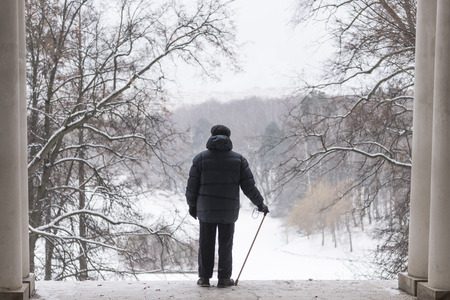 The man is an elderly pensioner standing in the arch with his back. In the winter in the park. Tsaritsyno, Moscow.の写真素材