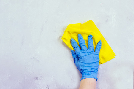 Woman in protective gloves cleaning kitchen table with rag.  Day of cleanliness and cleaning.の写真素材