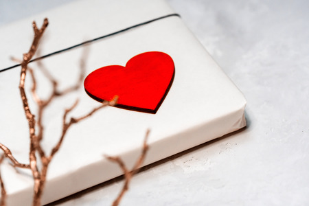 A gift box of craft paper tied with a lace. A wooden red heart. Dry twigs on the day of the holy valentine.の写真素材