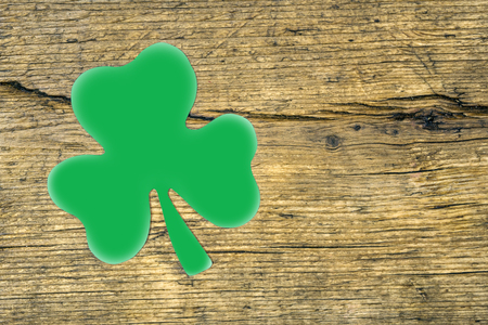 Paper sheet symbol of St. Patrick's Day. Green clover in the shape of heart. Wooden background.の写真素材