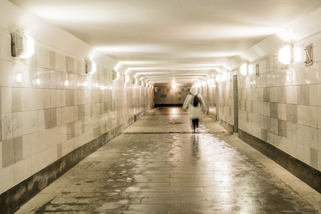 The underground passage is faced with gray granite and marble. People cross the road through the tunnel. The ladder is up. City center.の写真素材