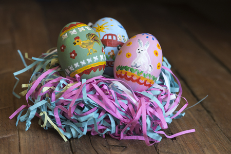 Painted eggs lie in a basket, wooden background, easterの写真素材