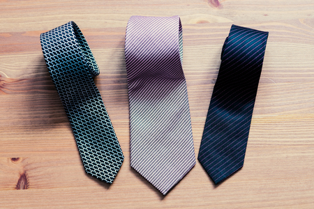 three men's tie rolled into a roll on a wooden backgroundの写真素材