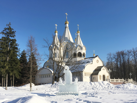 Russia, Novodrozhzhino, 03-24-2018. Ice sculpture on the background of a white temple. Clear frosty day. Blue sky. のeditorial素材
