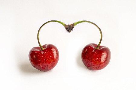 Berries of ripe cherries, drops of dew, a heart shape, two pieces. Studio white background, valentine dayの写真素材