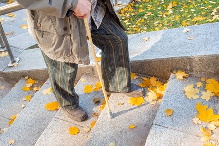 elderly man climbs the marble stairs, city park in the fallの写真素材