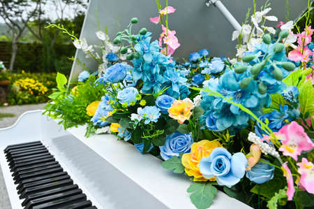Artificial flower decoration on white piano.の写真素材