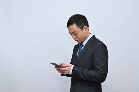 Asian male office worker, using mobile phone, white backgroundの写真素材