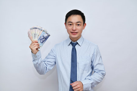 Asian male office worker holding New Taiwan dollars in red packets, White background.の写真素材