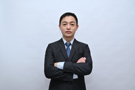 Close-up of upper body of asian male office worker, serious face, white backgroundの写真素材