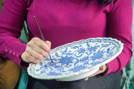 Female tile artist paints porcelain at workshop. Izmik, Turkey.のeditorial素材