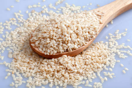 Wooden spoon of full sesame seeds on a white background,top view