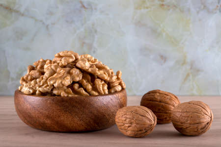 Bowl of walnuts and whole walnut kernels on color backgroundの写真素材