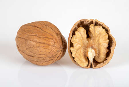 Cracked walnuts and whole walnuts on white background