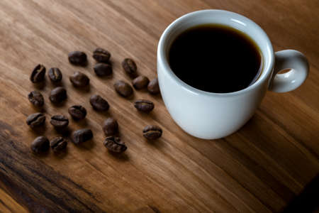 White cup of coffee with coffee beans on wooden backgroundの写真素材