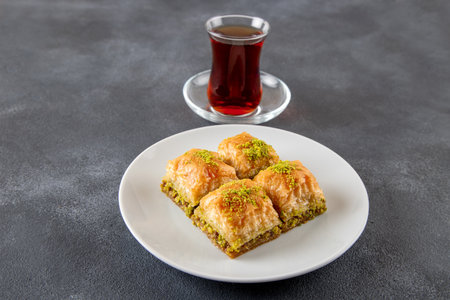 Pistachio baklava on a white plate with Turkish teaの写真素材