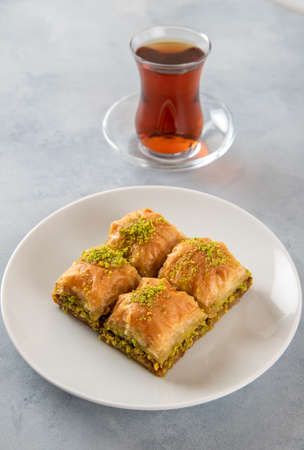 Pistachio baklava on a white plate with Turkish tea.Traditional Turkish baklava and tea on a white backgroundの写真素材