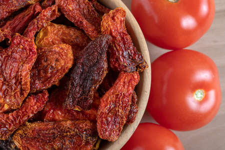 Fresh tomatoes and sun dried tomatoes with on wooden backgroundの写真素材