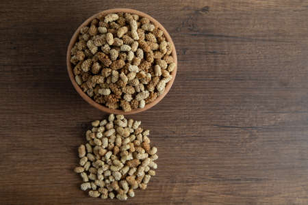 Bowl full of dried mulberry on a wooden background