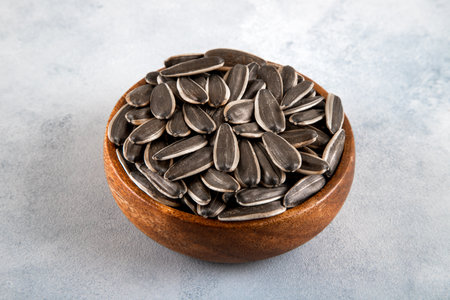 Black sunflower seeds in a bowl, on bright background,closeup
