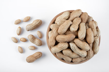 Bowl full of shelled and roasted peeled peanuts on white background, closeup