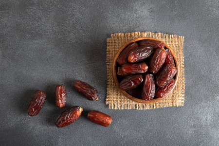 Dried dates fruits in bowl on dark background. Top view.の写真素材