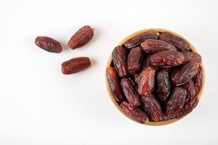 Dates fruit in wooden bowl isolated on white background. Top view.の写真素材