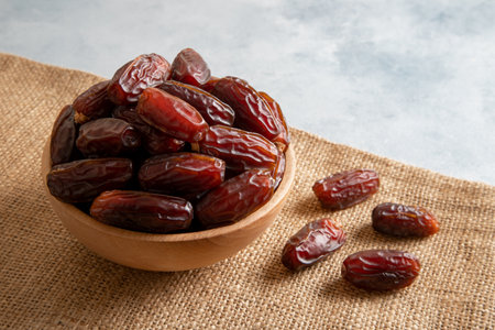 Date fruits in wooden bowl on bright background,closeup