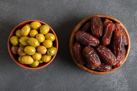 Date fruit with a bowl of green olive on a black background.の写真素材