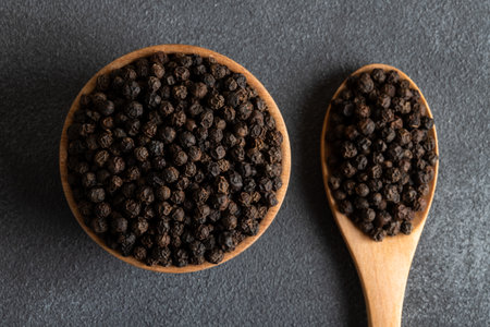 Bowl full of black pepper on a black background,top view