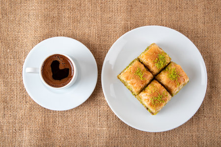 Pistachio baklava on a white plate with Turkish coffee.A plate of traditional baklava on burlap sackの写真素材