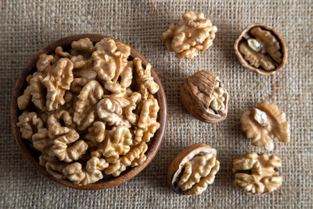 Walnuts in a wooden bowl on a burlap background. Top view.