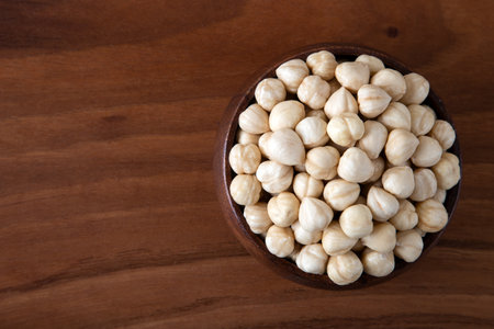 Top view of a bowl full of peeled hazelnuts on wooden tableの写真素材