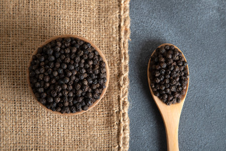 A bowl and a spoon with black peppercorns, top viewの写真素材