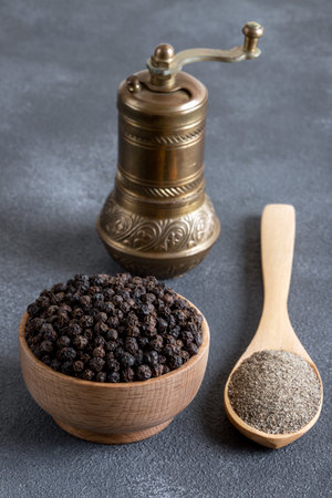 Bowls of black peppercorns on a black background and a metal grinderの写真素材
