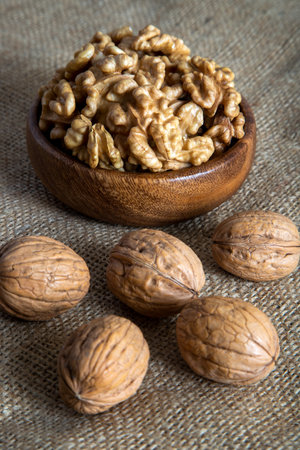Walnuts in a wooden bowl on a burlap background. Selective focus.の写真素材