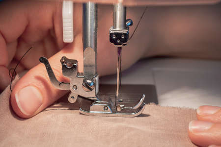 Fabric sewn on the sewing machine. Photo focused on the needle of the sewing machine where the...