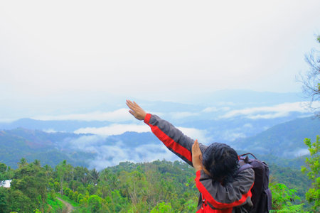 traveler hiking in the hills on blue sky background, traveler lifted his hands upの写真素材