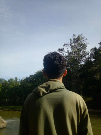 rear view of a man looking at trees in the wild
