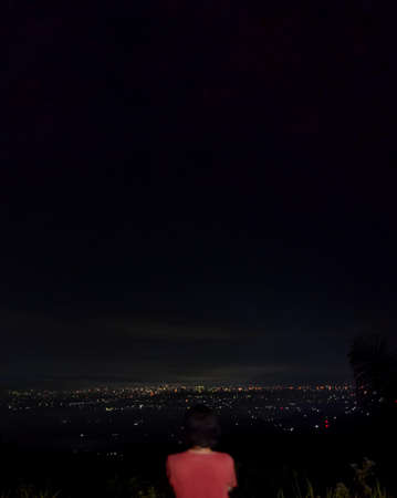 back view of a man on a mountain at nightの写真素材