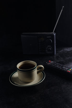 cup of hot coffee, vintage radio, and remote on black backgroundの写真素材