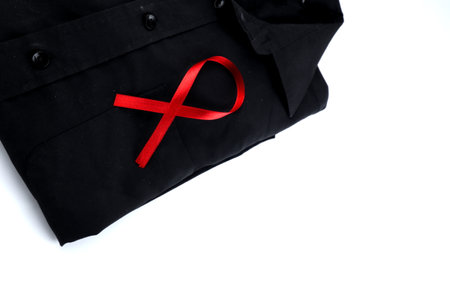 Red ribbon on a black shirt on a white background. Modern treatment and healthcare. AIDS awareness conceptの写真素材